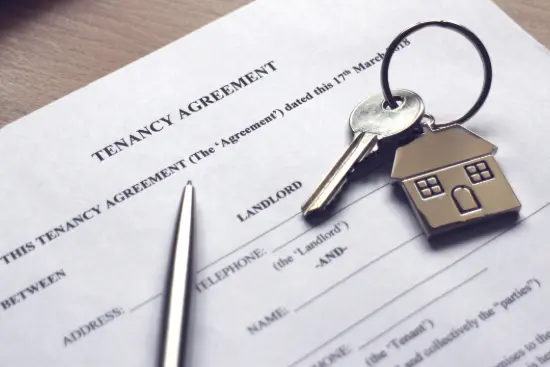 Key with a key chain of a house on top of a tenancy agreement