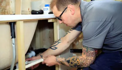 A plumber fixing an leak under a bath