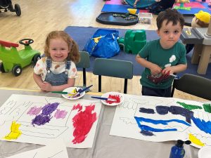 Two of the children, one girl, one boy, are painting pictures.
