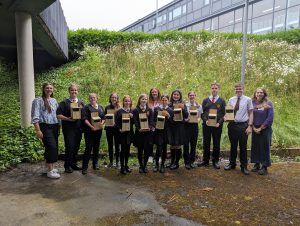 10 young people and 3 teachers hold the bird boxes.