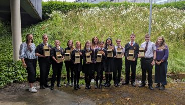 10 young people and 3 teachers hold the bird boxes.