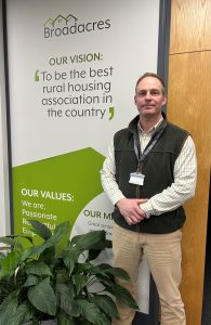 Paul stood in front of a wall with the writing saying the Broadacres vision; "To be the best rural housing association in the country"