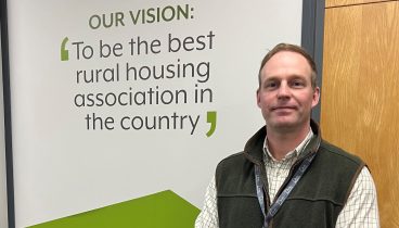 Paul stood in front of a wall with the writing saying the Broadacres vision; "To be the best rural housing association in the country"