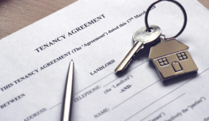 Key with a key chain of a house on top of a tenancy agreement